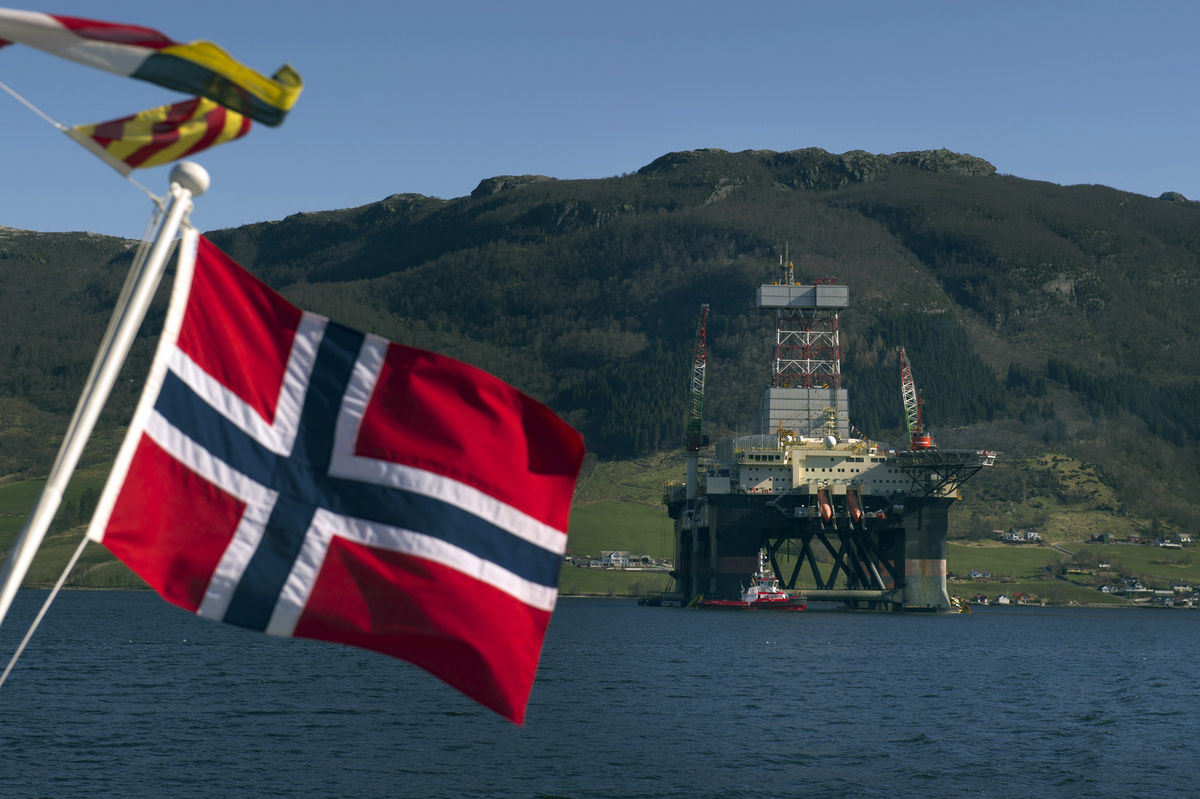 إنتاج النفط والغاز في النرويج - علم النرويج وخلفه حقل نفطي بحري