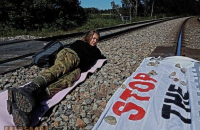 ناشطة أسترالية تتظاهر على شريط السكك الحديدة لوقف عبور قطارات الفحم في أستراليا - الصورة من موقع جماعة بلوك ايد