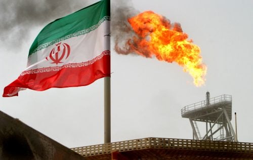 A gas flare on an oil production platform is seen alongside an Iranian flag