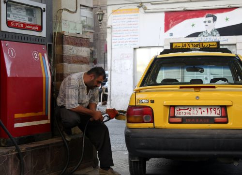 عامل يمون سيارة بالبنزين في إحدى محطات الوقود في سوريا- 
