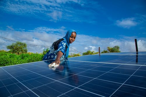سيدة تنظف ألواحًا بإحدى محطات الطاقة الشمسية في أفريقيا