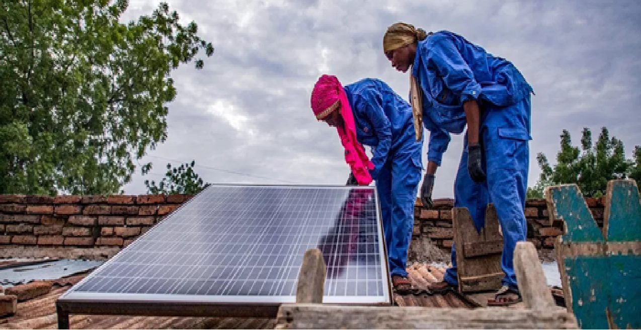 نساء يركّبن لوحًا شمسيًا على سطح منزل في مدينة أم تيمان التشادية