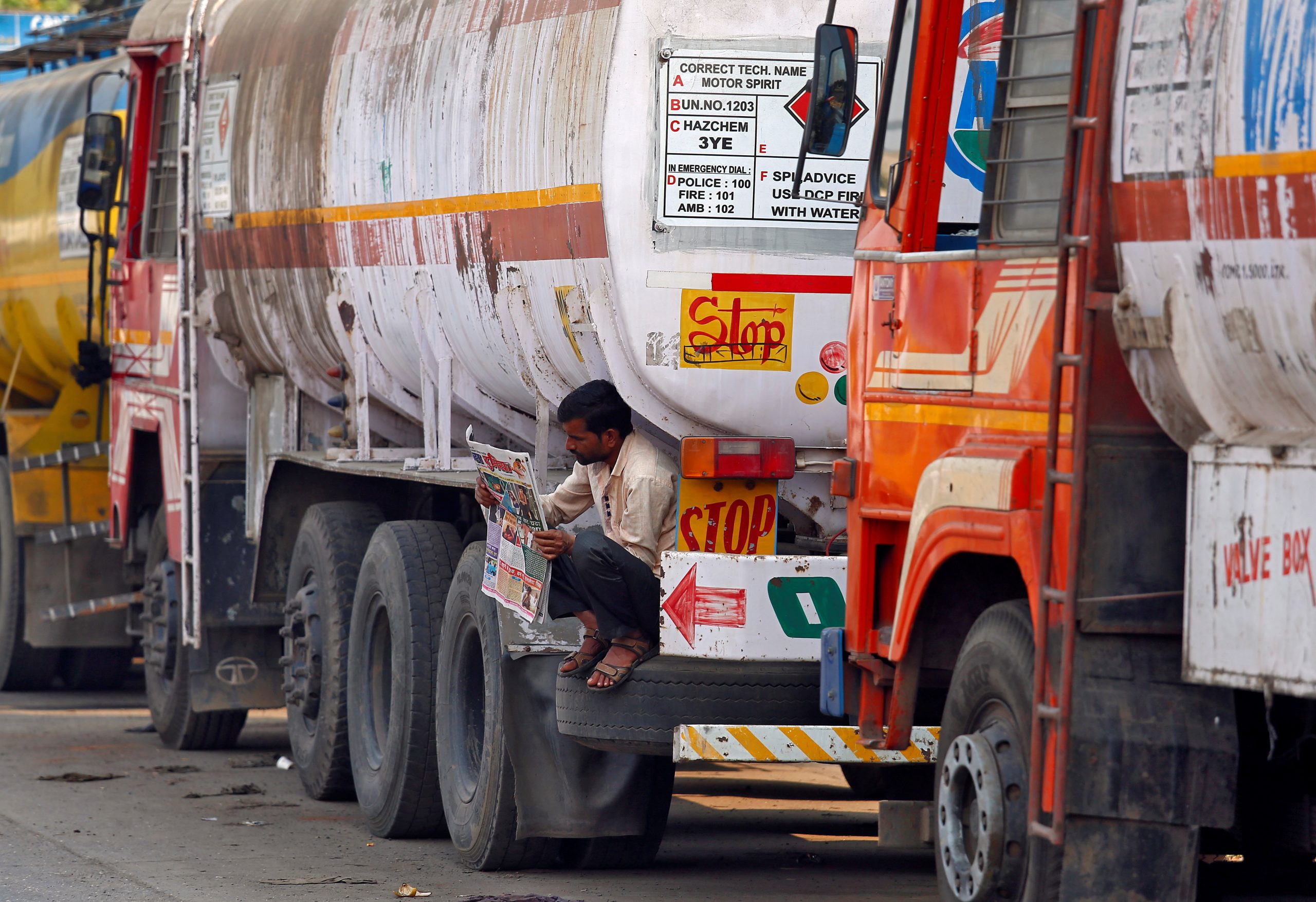 مواطن هندي يقرأ صحيفة بجوار شاحنة لنقل النفط 