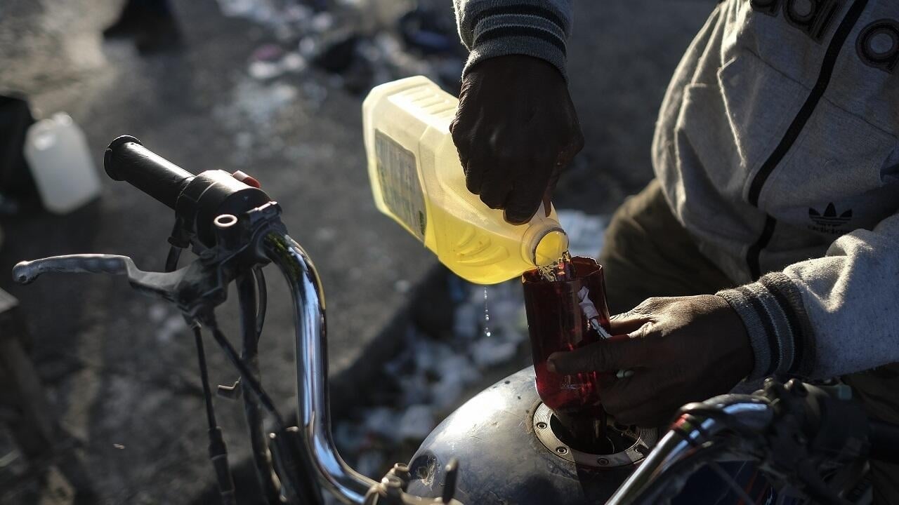 رجل يضع وقودًا من السوق السوداء في دراجة بعد إلغاء دعم الوقود في نيجيريا