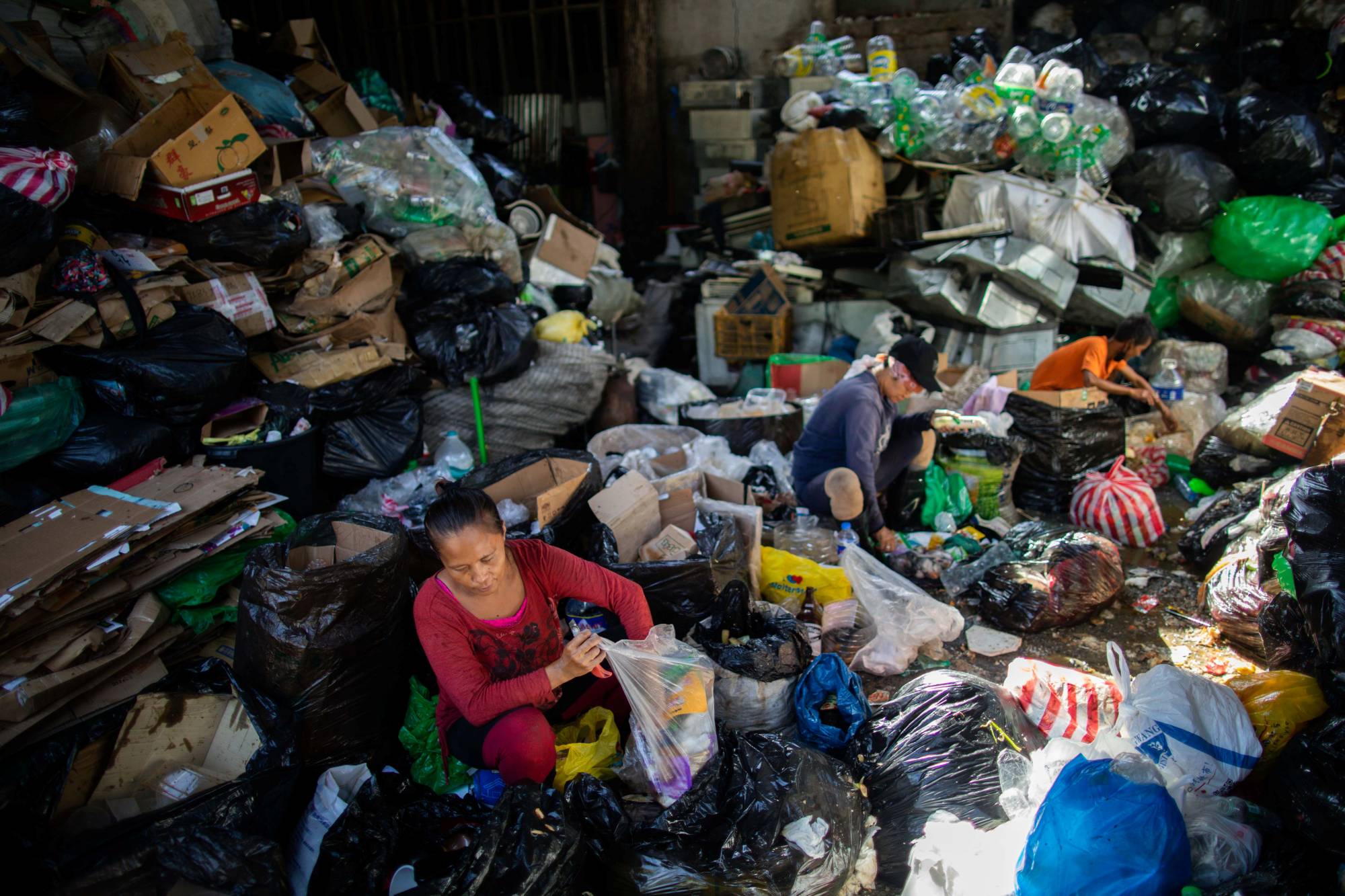 عمال يفرزون النفايات والقمامة تمهيدًا لإعادة تدوير البلاستيك - الصورة من The Japan Times