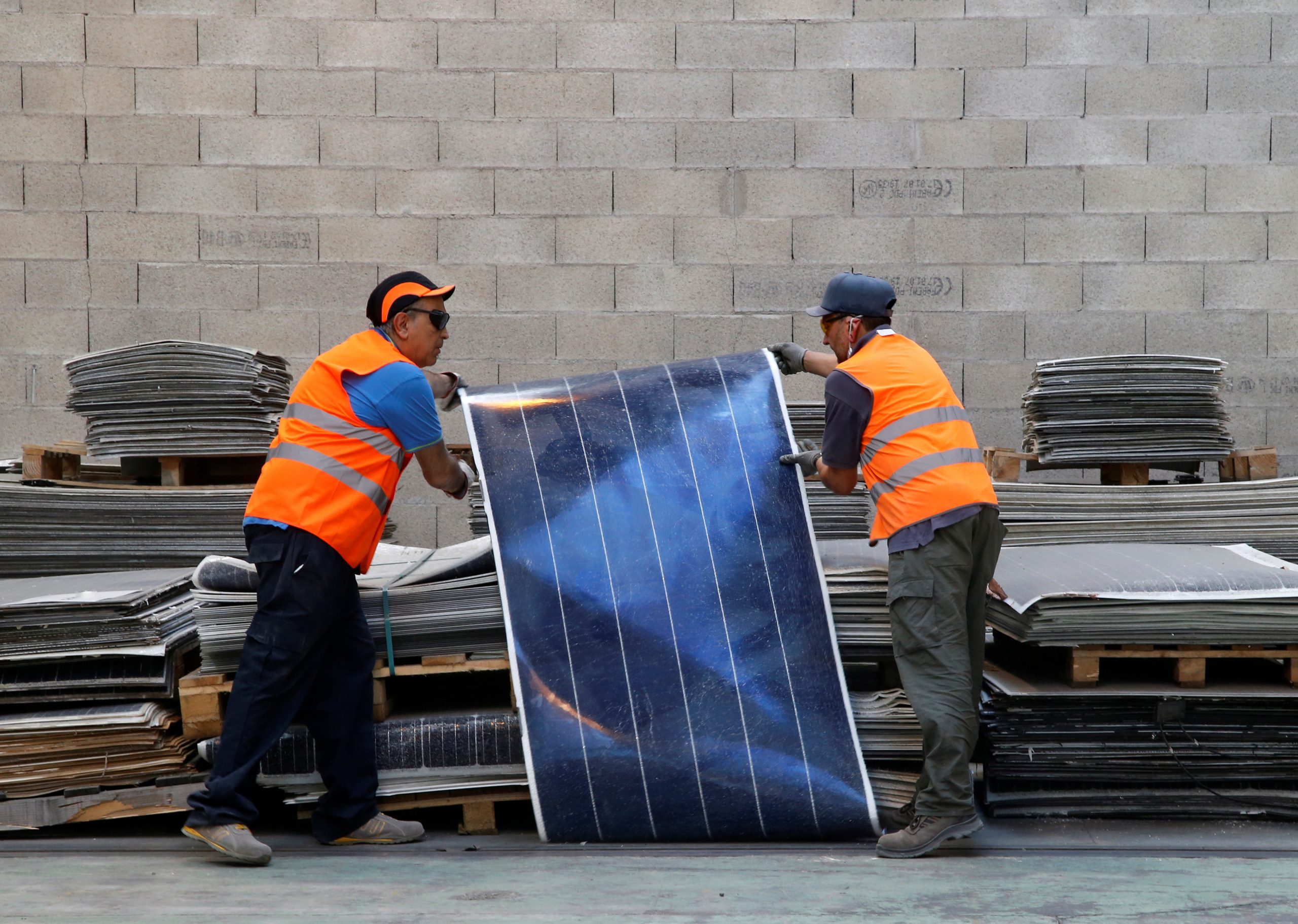 عمال يجمعون ألواحًا شمسية متهالكة