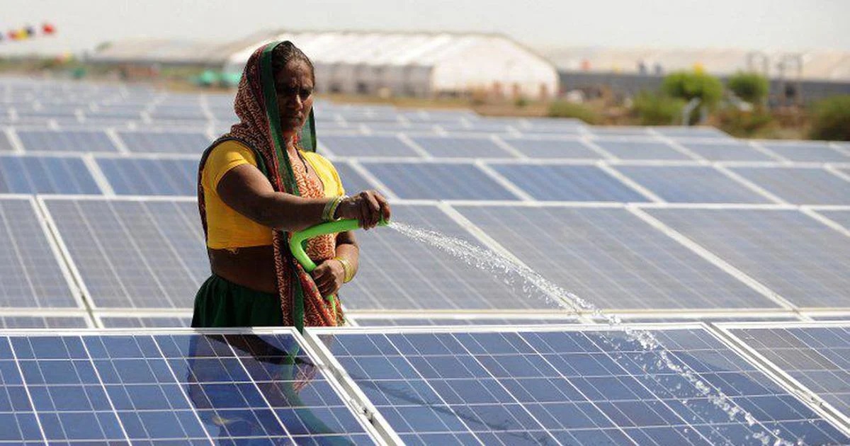 عاملة تغسل الألواح الشمسية بالماء في محطة في الهند