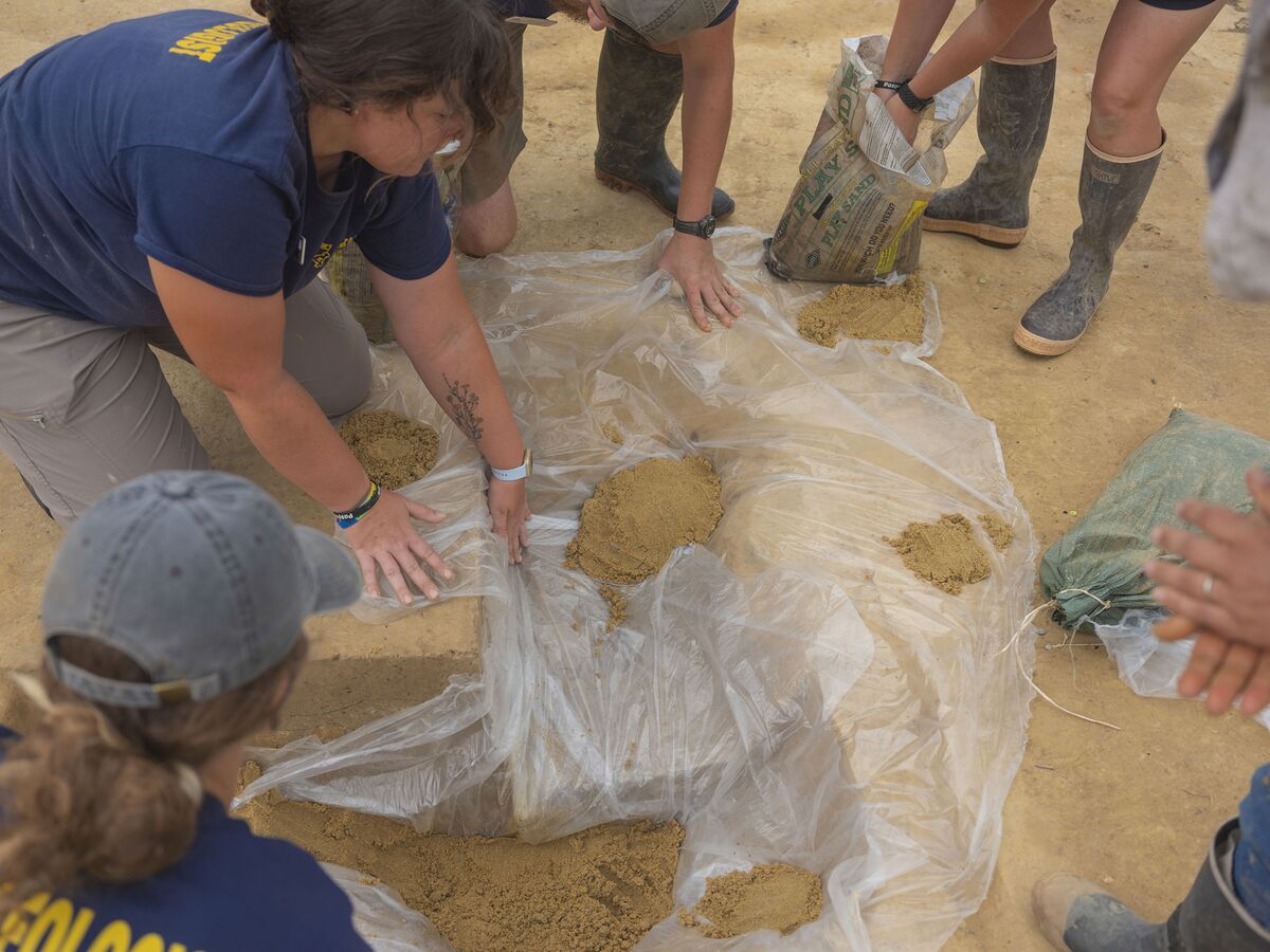 فريق من الباحثين يحمون موقع الحفر من تسرب المياه.