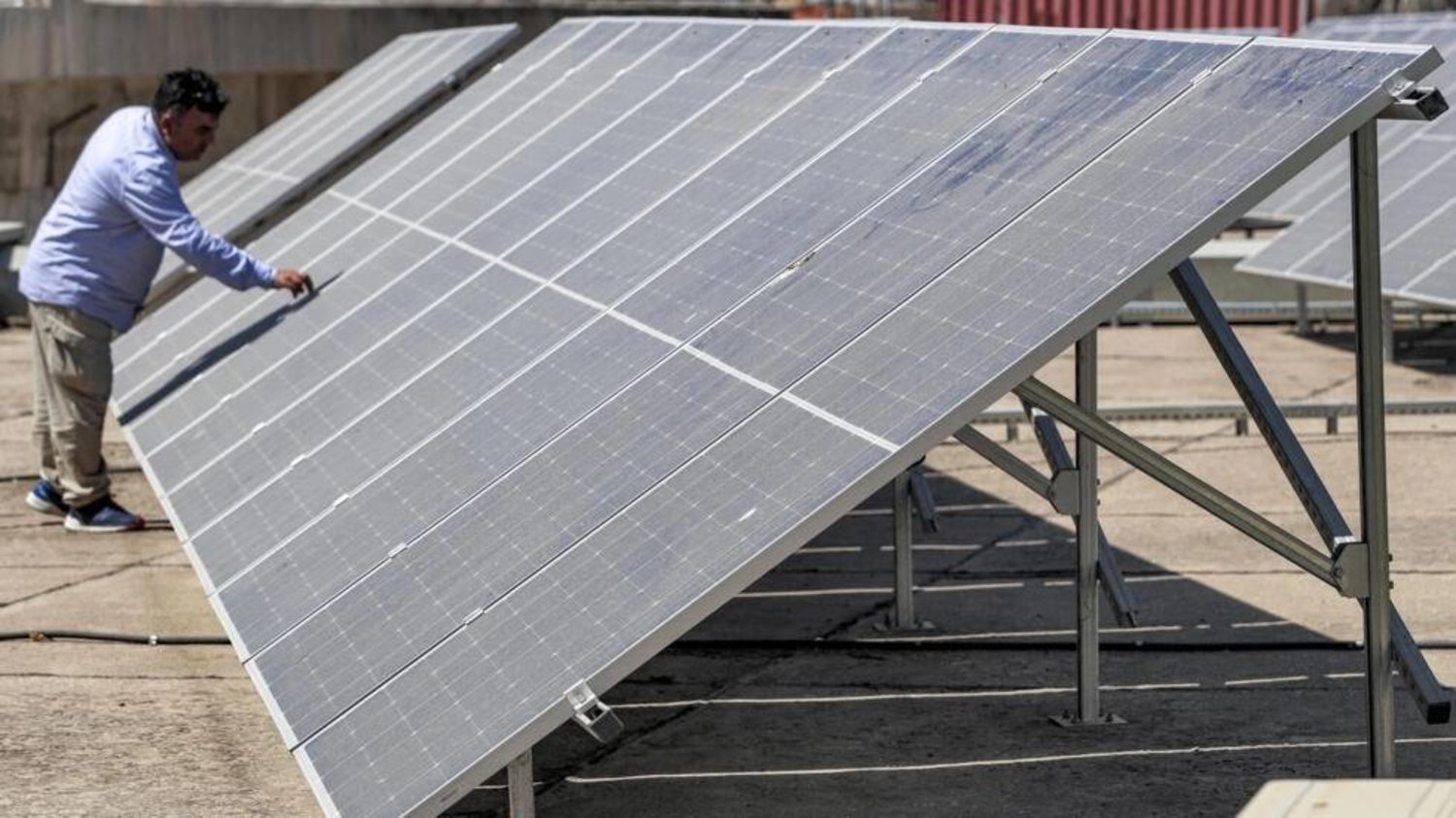مهندس يفحص ألواحًا شمسية على سطح مبنى في العراق