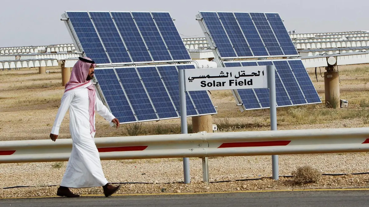 مواطن يسير قرب محطة طاقة شمسية في السعودية