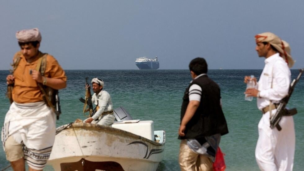 مسلحون على أحد شواطئ اليمن وفي الخلفية إحدى الناقلات
