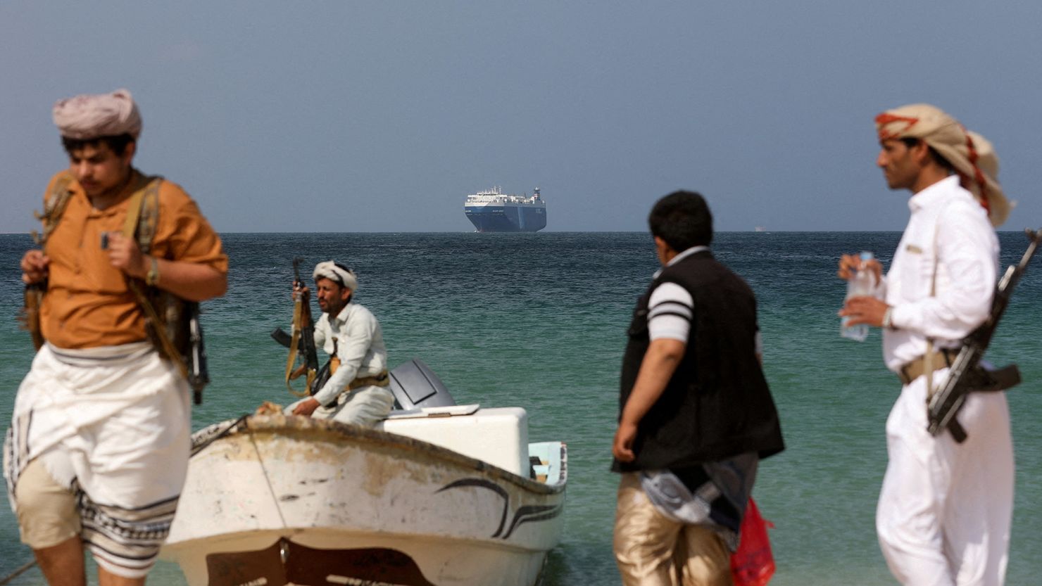 مسلحون يمنيون وبالخلفية السفينة غالاكسي ليدر التي استولى الحوثيون عليها في ديسمبر