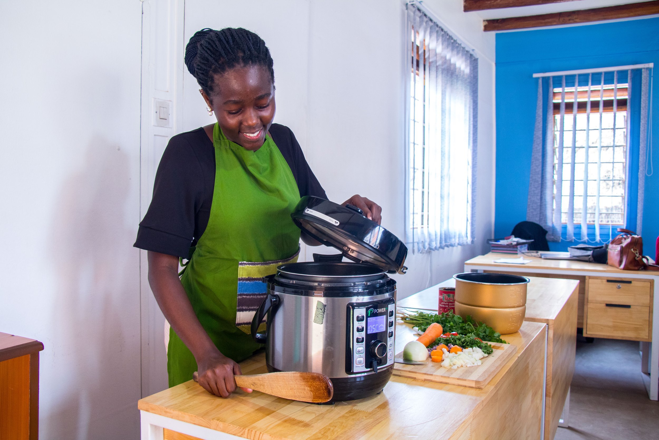 امرأة أفريقية تستعمل قدرًا كهربائية في الطهي 