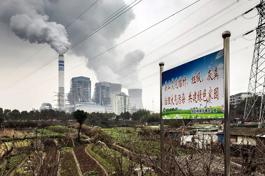 لافتة تحذر من حرق القمامة وفي الخلفية محطة فحم في الصين