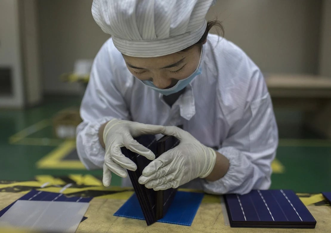 عاملة تقنية صينية تعاين خلية مستعملة في الألواح الشمسية - الصورة من موقع إي آند إي