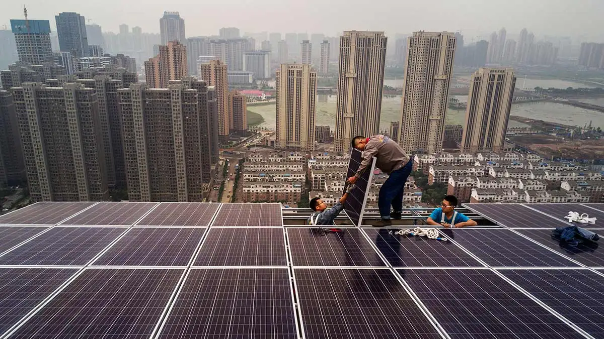 عاملان أثناء تركيب ألواح شمسية فوق الأسطح في الصين