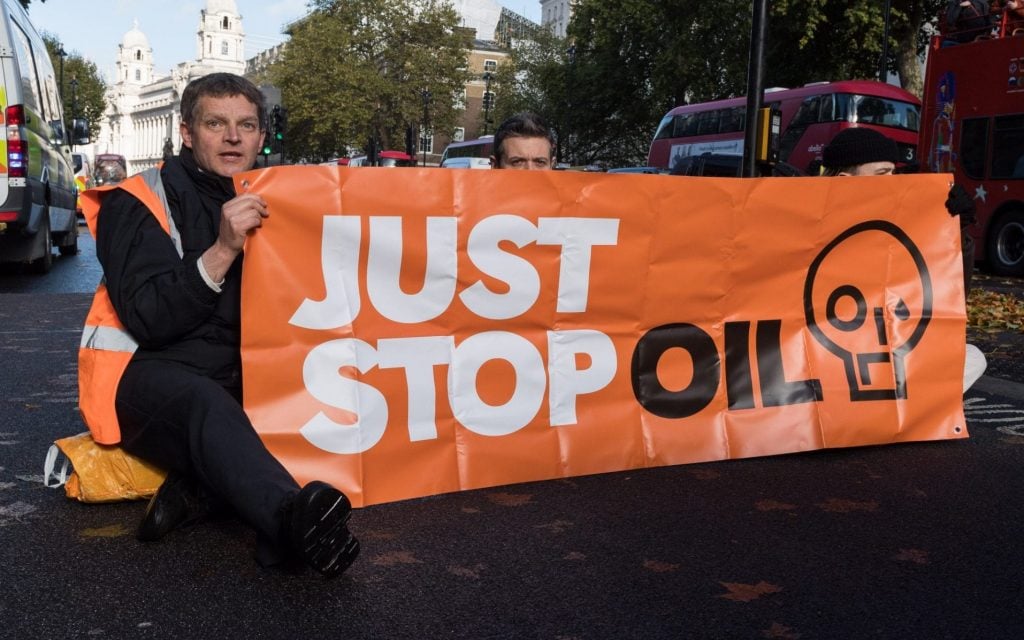 مواطنان يرفعان لافتة حملة جاست ستوب أويل المناهضة للوقود الأحفوري 