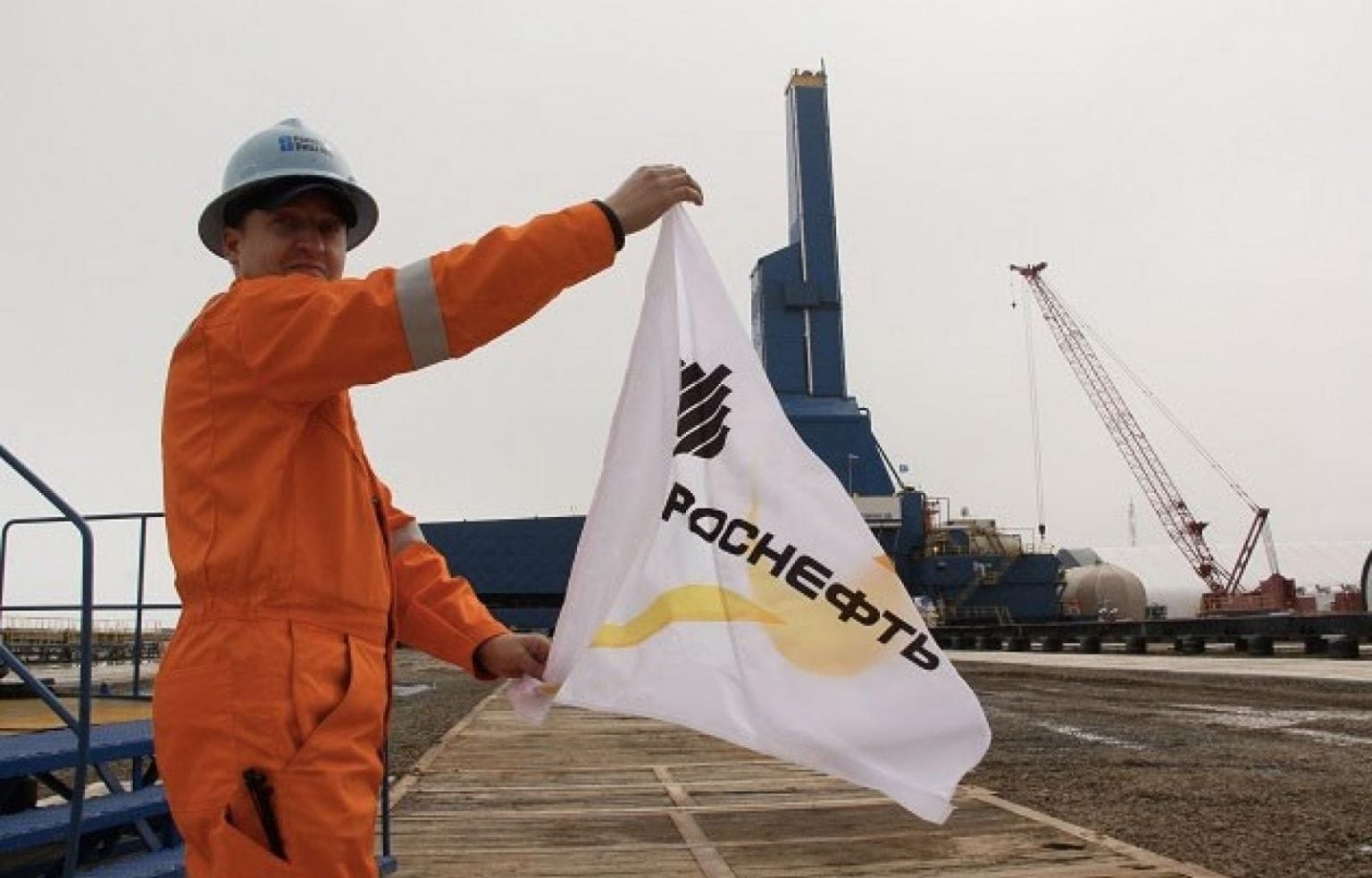 عامل يرفع لافتة عليها شعار روسنفط