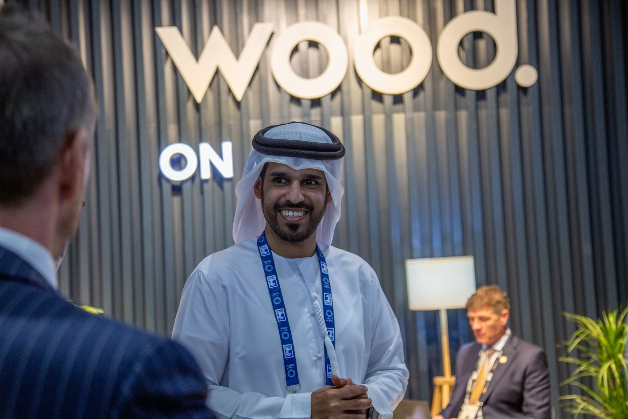 ممثل لإحدى شركات مجموعة أدنوك بجوار شعار شركة وود