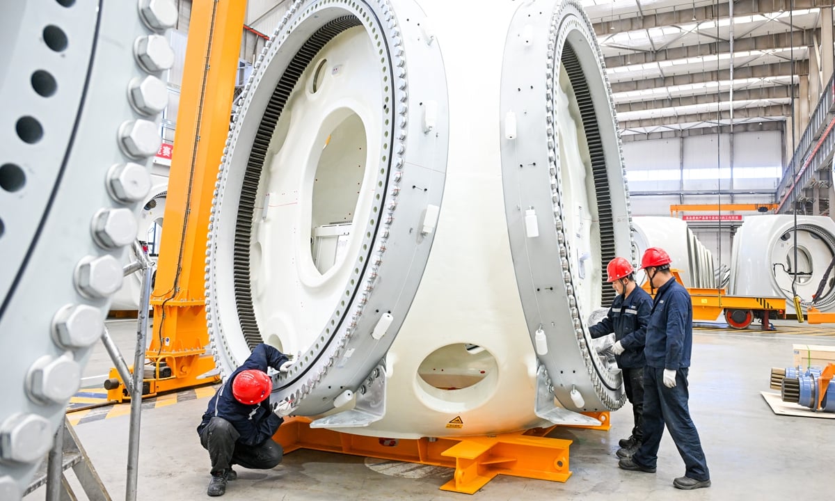 عمال في أثناء تجميع توربين في مصنع توربينات رياح في الصين