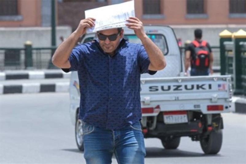 شخص مصري يضع ورقة على رأسه ليحمي نفسه من الشمس الحارقة