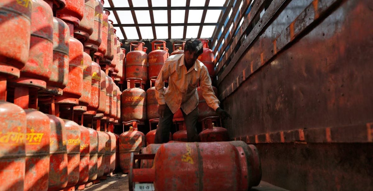 عامل يُفرغ أسطوانات غاز النفط المسال المستعمَلة في الطهي من شاحنة في الهند