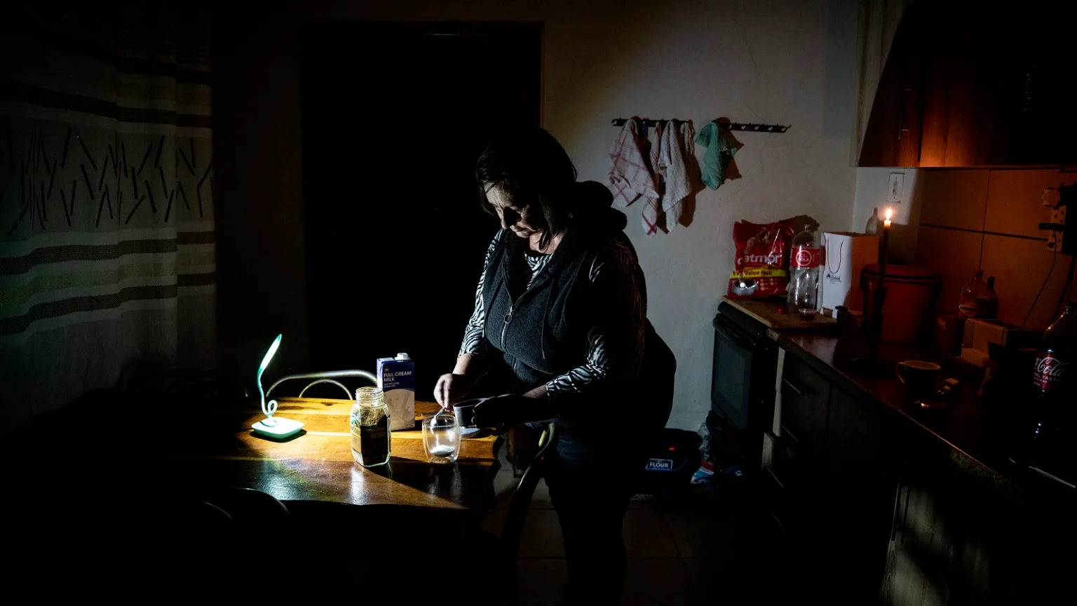 سيدة تصنع فنجانًا من القهوة في منزلها خلال انقطاع التيار الكهربائي في جنوب أفريقيا